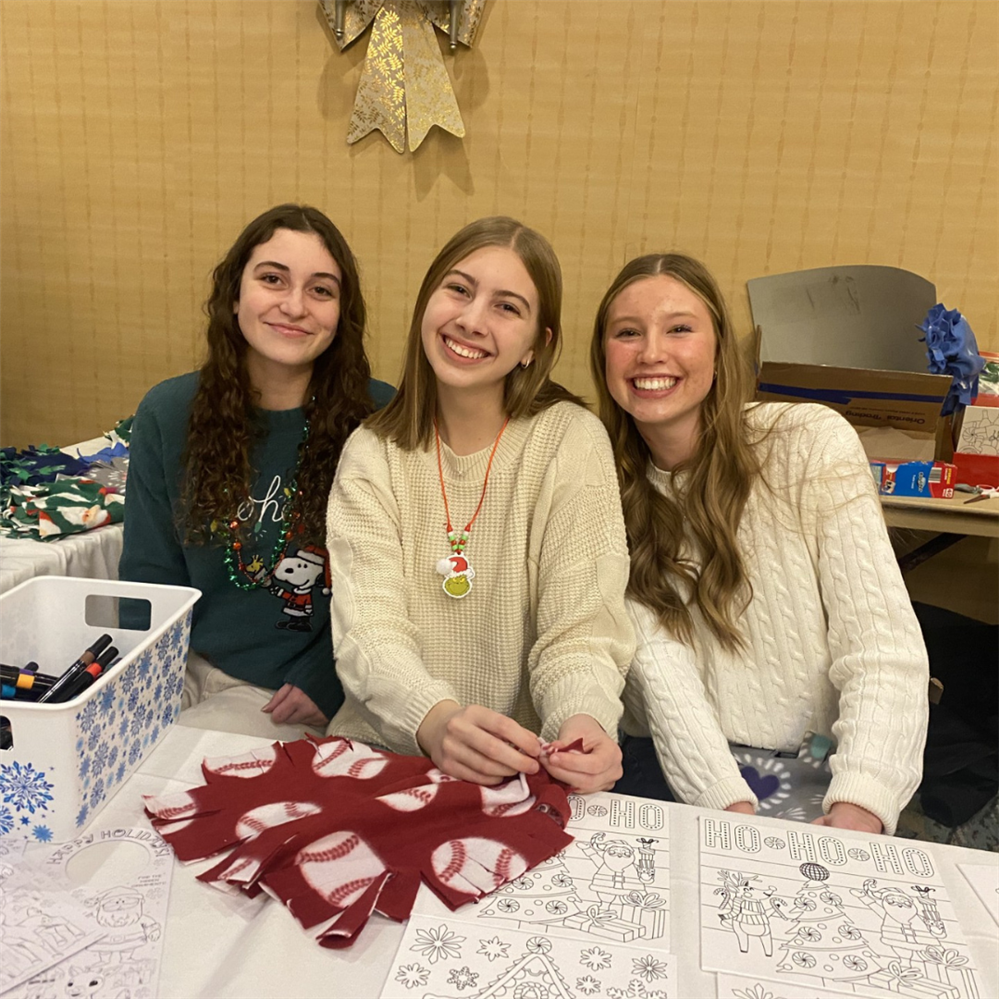 Three New Vision Medical Careers students are smiling for the camera at a holiday event.